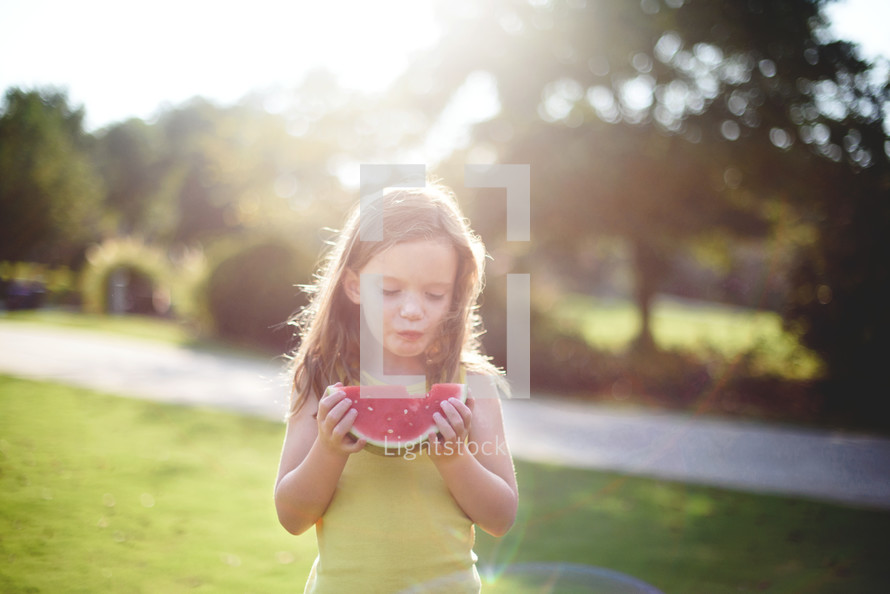 a girl child eating a watermelon outdoors 