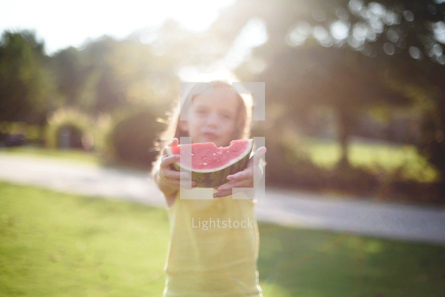 a girl child holding a slice of watermelon 