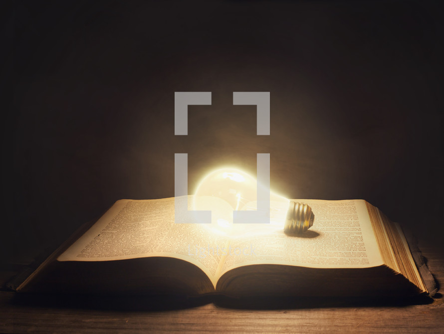 glowing lightbulb on an open Bible 