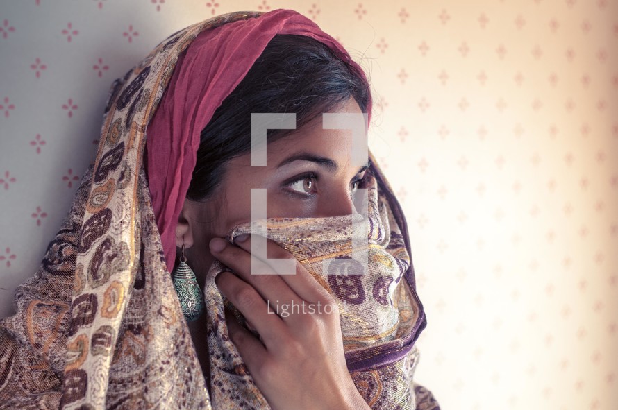 Middle eastern women revealing her eyes and covering the lower part o fher face with her shawl.