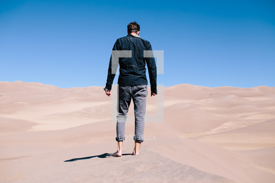 man standing barefoot in the desert 