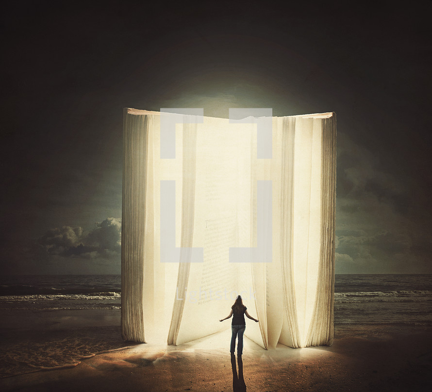 woman standing in front of a giant glowing Bible on a beach