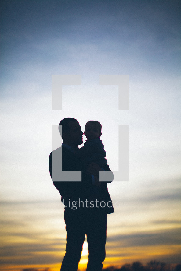 silhouette of a father holding his toddler son