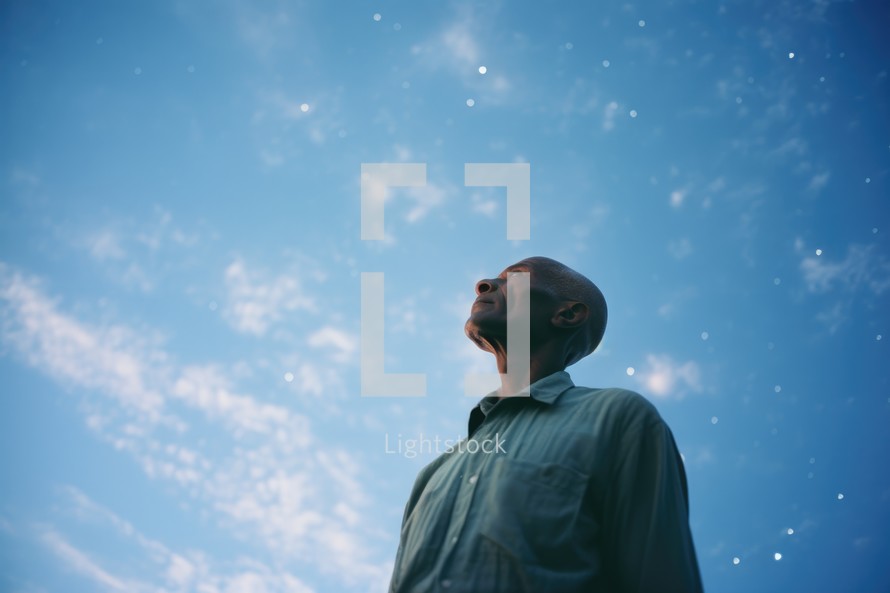 Low angle view of man looking away against blue sky with white clouds