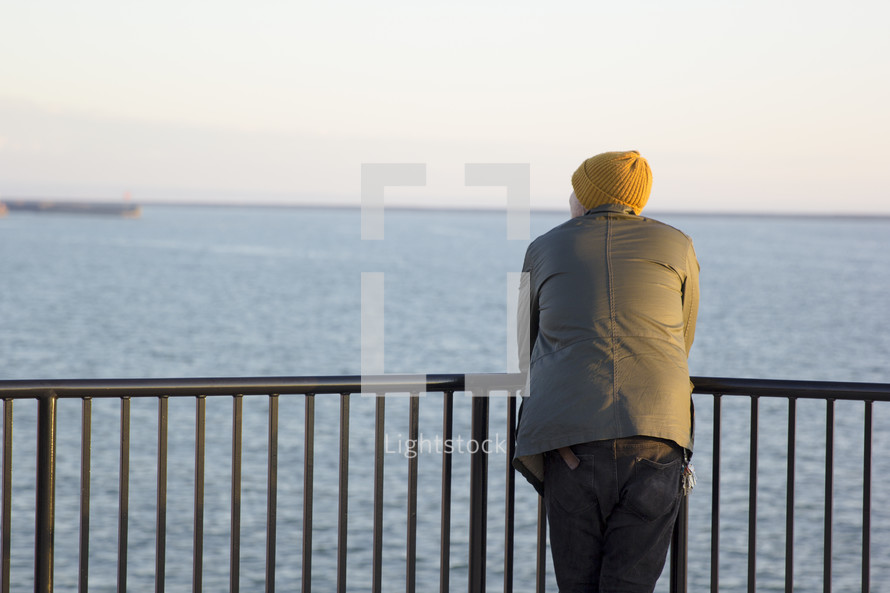 a man looking over a railing at water 