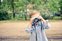 A little boy photographs the photographer with a toy camera.