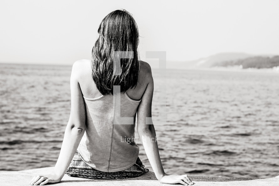 woman sitting on the edge of a dock 