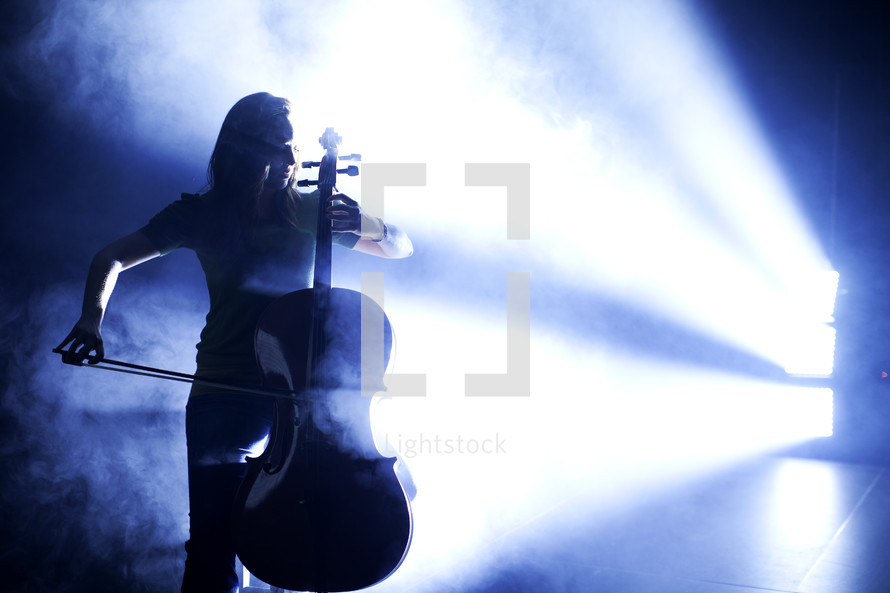 woman in a spot light playing a cello 
