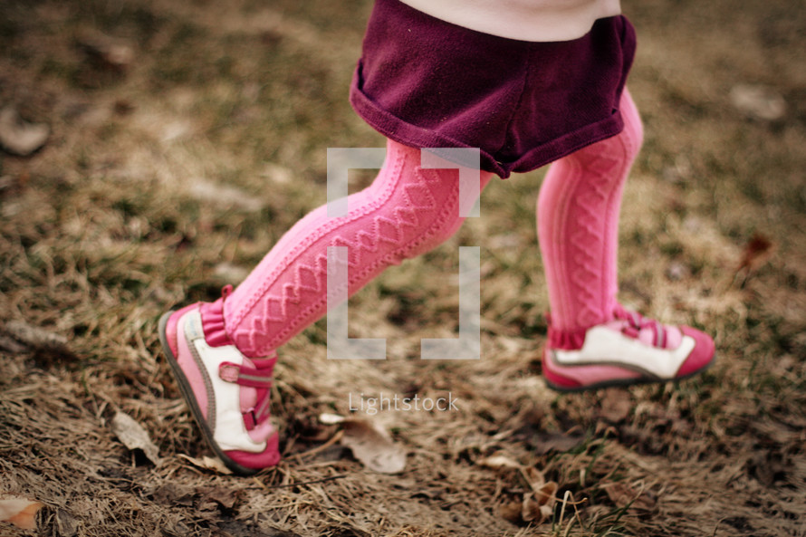 A little girl running in pink tights.