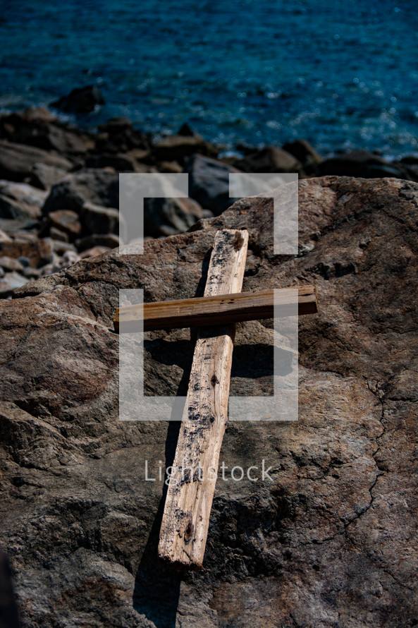 wood cross on a rock by the ocean 
