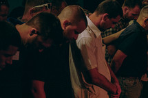 congregation with heads bowed in prayer 