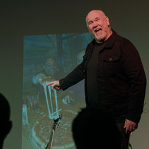a man narrating slide show on stage 