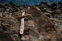 wooden cross on a rock by the ocean 