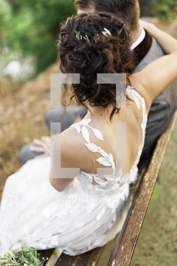 bride and groom sitting on a bench outdoors 