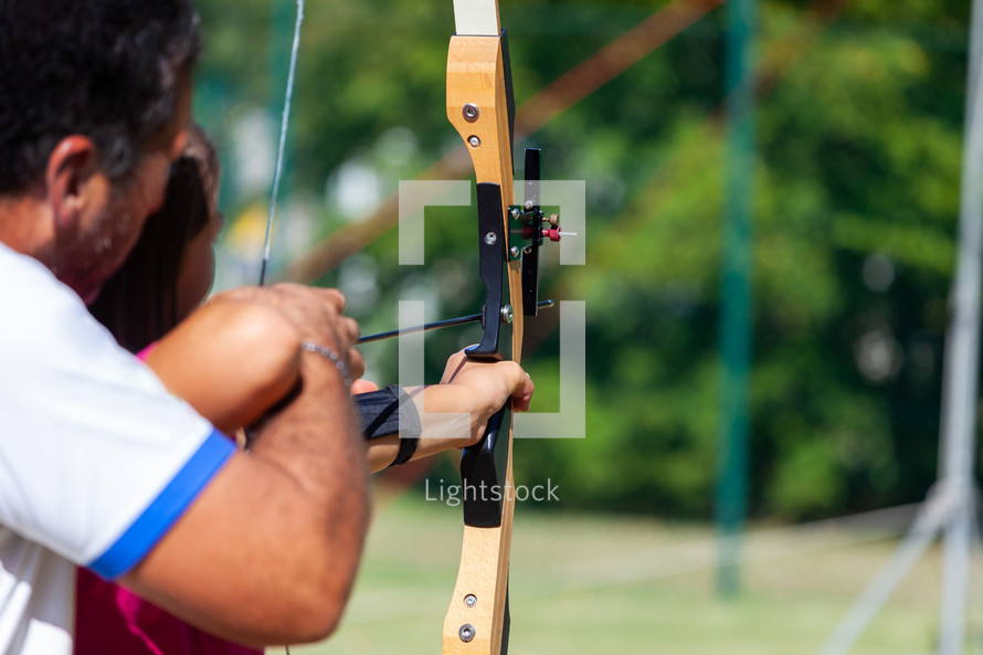 Archery course. The teacher teaches the student to aim at the goal.