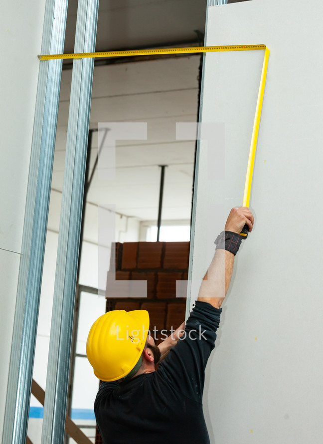 Worker at work in the construction of a plasterboard wall.