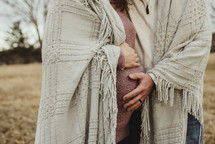 portrait of an expecting couple under a blanket 