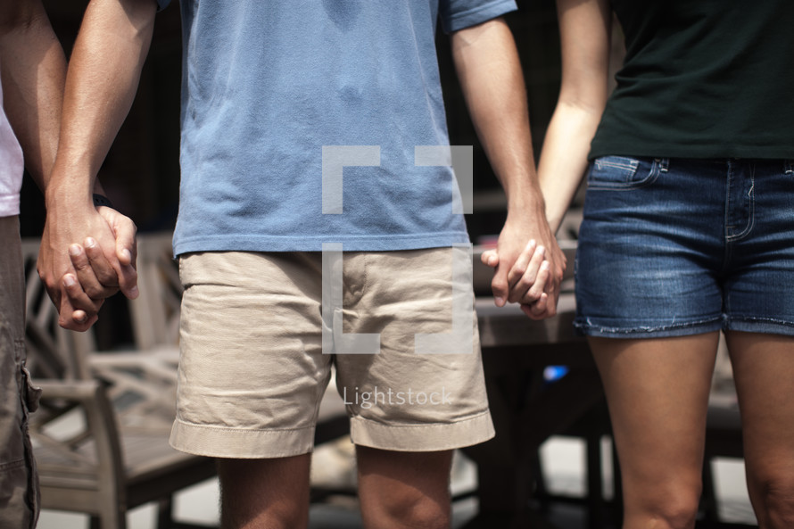 holding hands in prayer at an outdoor summer party 