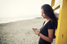 teenager while using the smartphone on the beach