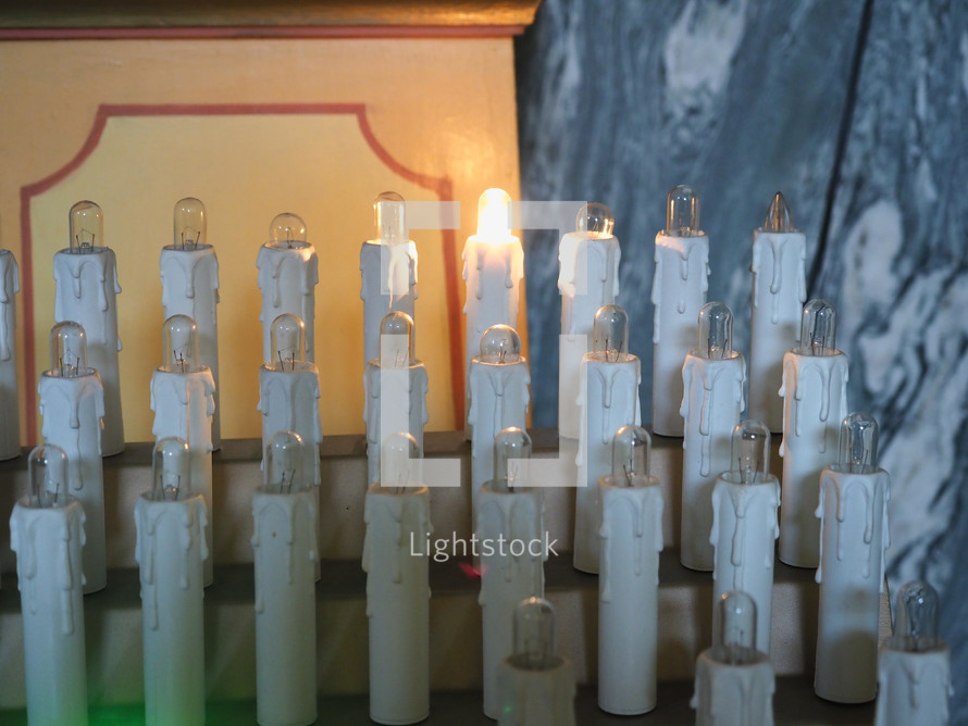 electric candles lit by worshippers in a Christian church