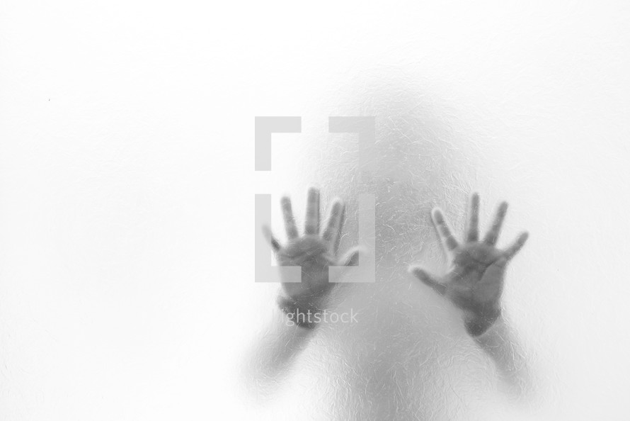 child's hands through frosted glass