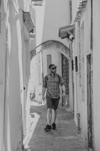 man walking down a narrow alley in Greece 
