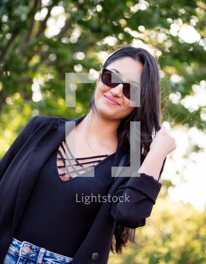 Woman in black shirt, blazer, and jean skirt with sunglasses