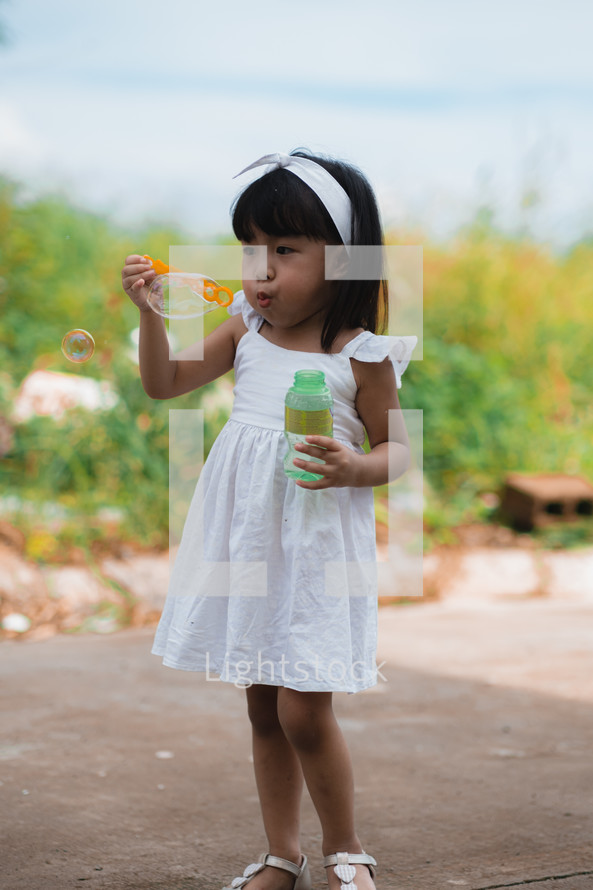 toddler girl blowing bubbles outdoors 