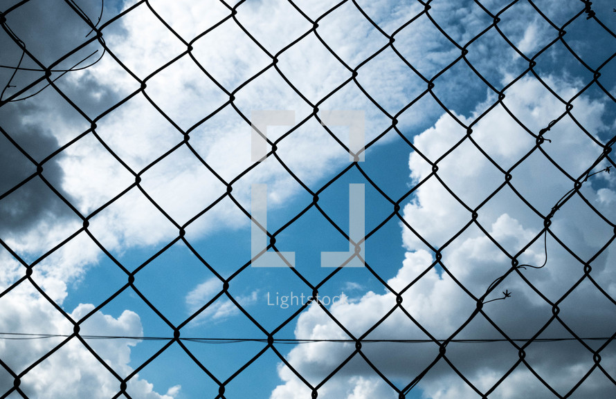 clouds through a chain link fence 
