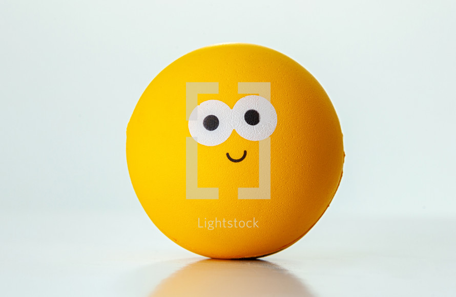 Yellow ball with a happy expression on a white background representing happiness and joy