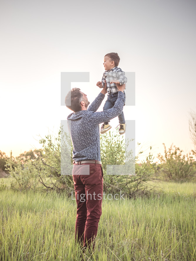father holding up a toddler boy 