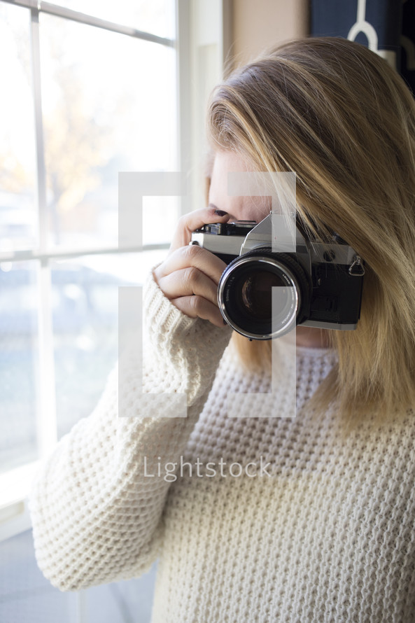 a woman in a sweater taking a picture with a camera 