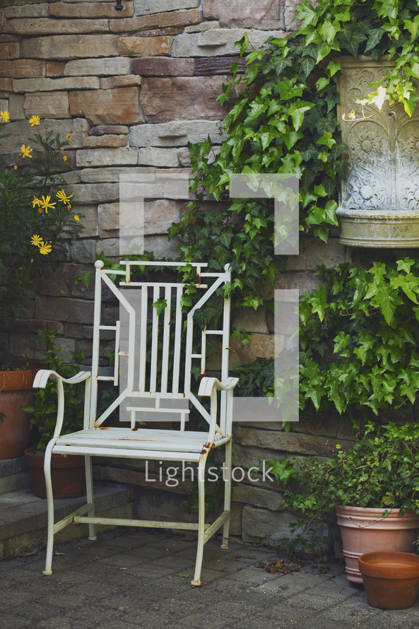a chair on a patio and ivy growing up the wall 
