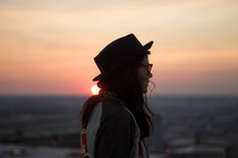 side profile of a woman in a hat at sunset 