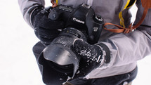 a man with a snowy glove holding a camera lens