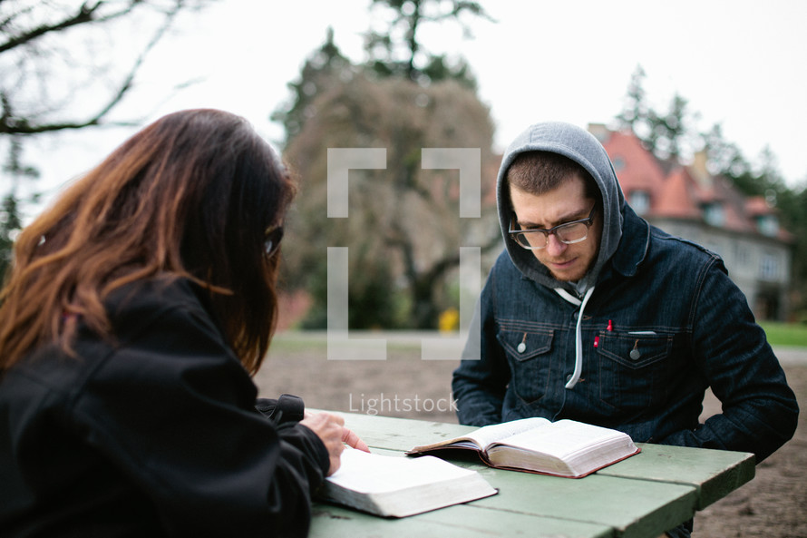 couple reading Bible's together on a picnic table 