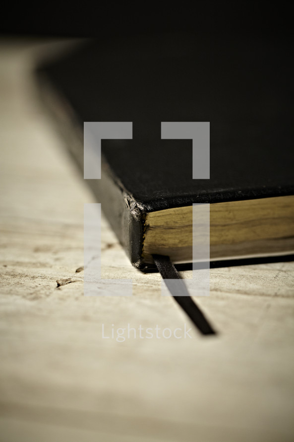 Black Bible and bookmark resting on a table 