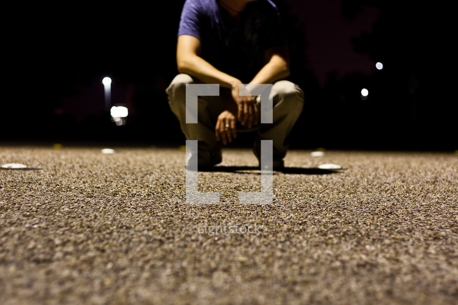 man crouched over gravel