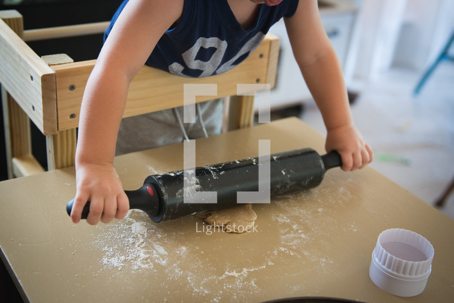 a toddler with a rolling pin and dough 