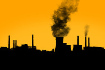 Dark harmful smoke from chimneys of power plant silhouette on sunset clear orange sky.