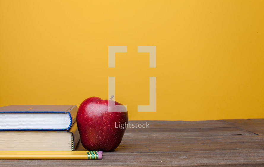 apple, books, and pencil on a teacher's desk 