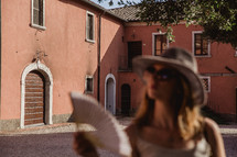 A woman fanning herself in a courtyard in Italy