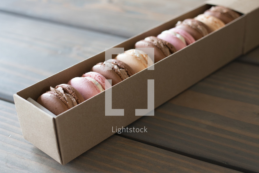 A box of macarons on a wooden table.