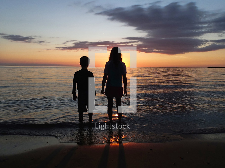 kids standing on a beach at sunset 