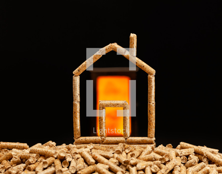 Miniature house made with wood pellets. Heating concept with combustion chamber in the background.
