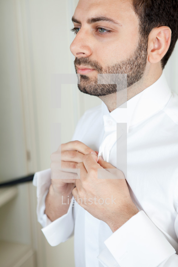 man getting ready buttoning his shirt 