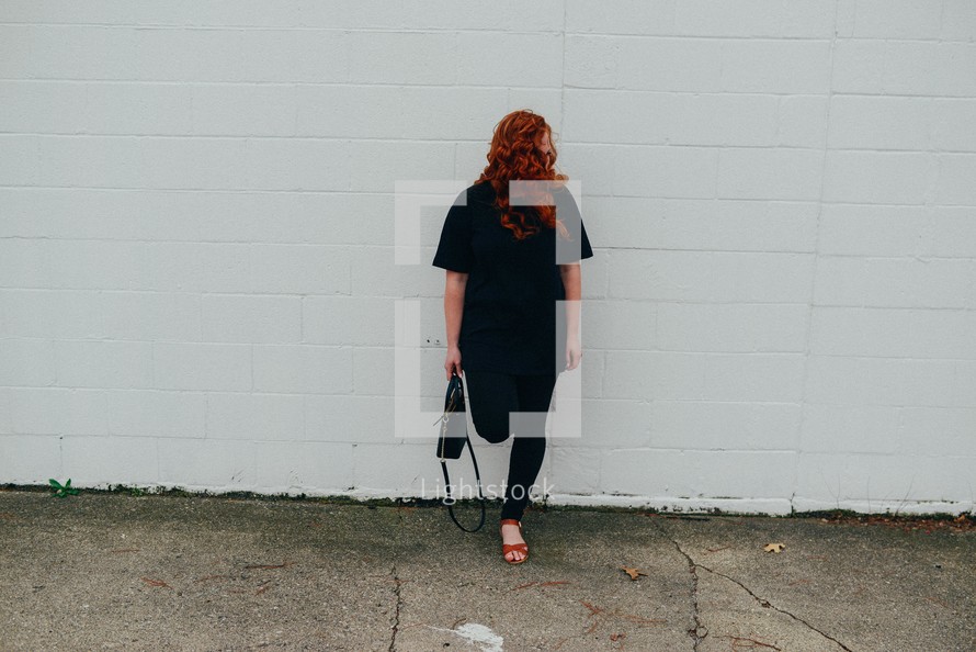 redhead woman standing in front of a white wall 