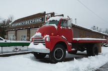 A vintage red pickup truck in the snow