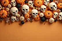 Halloween background with pumpkins, skulls and autumn leaves on orange background