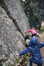 kids pretending to climb a rock cliff 